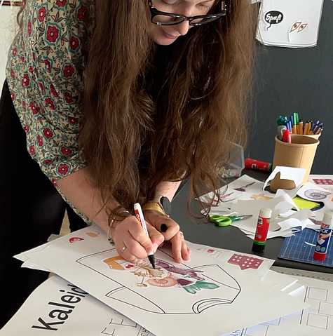 Workshopteilnehmerin zeichnet und visualisiert Ideen für das neue Erscheinungsbild auf einem großen Papierbogen.