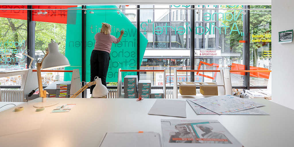 Frau beschriftet die Fensterfront des mobilen Workshopraums