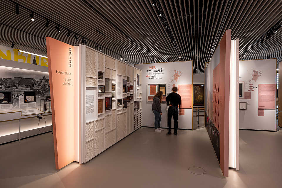 Besucher:innen zwischen Ausstellungselementen zu verschiedenen Epochen und Themen der Oldenburger Stadtgeschichte.“