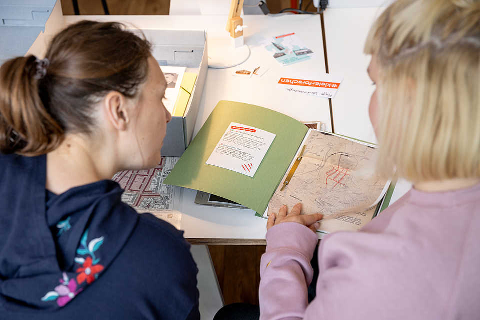 Teilnehmende recherchieren mit historischen Karten und Materialien zu Straßennamen
