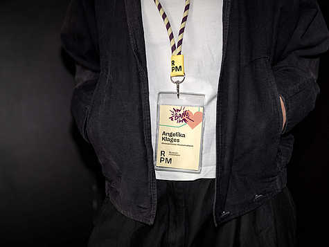 Badge vom RPM Museum mit illustrativen Gestaltungselementen und farbigen Textilbändern