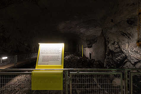 Ausstellungstafel mit Zeitzeugenbericht von Friedrich Kochheim aus dem Jahr 1952 in einem Stollenabschnitt der Gedenkstätte Mittelbau-Dora. Im Hintergrund eine zerstörte Mauer.“