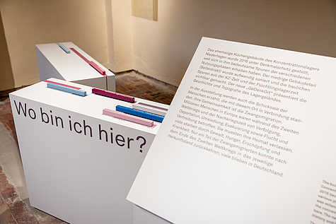 Zwei weiße Informationstafeln mit der Überschrift "Wo bin ich hier?". Im Hintergrund sind farbige Elemente auf den Tafeln sichtbar.