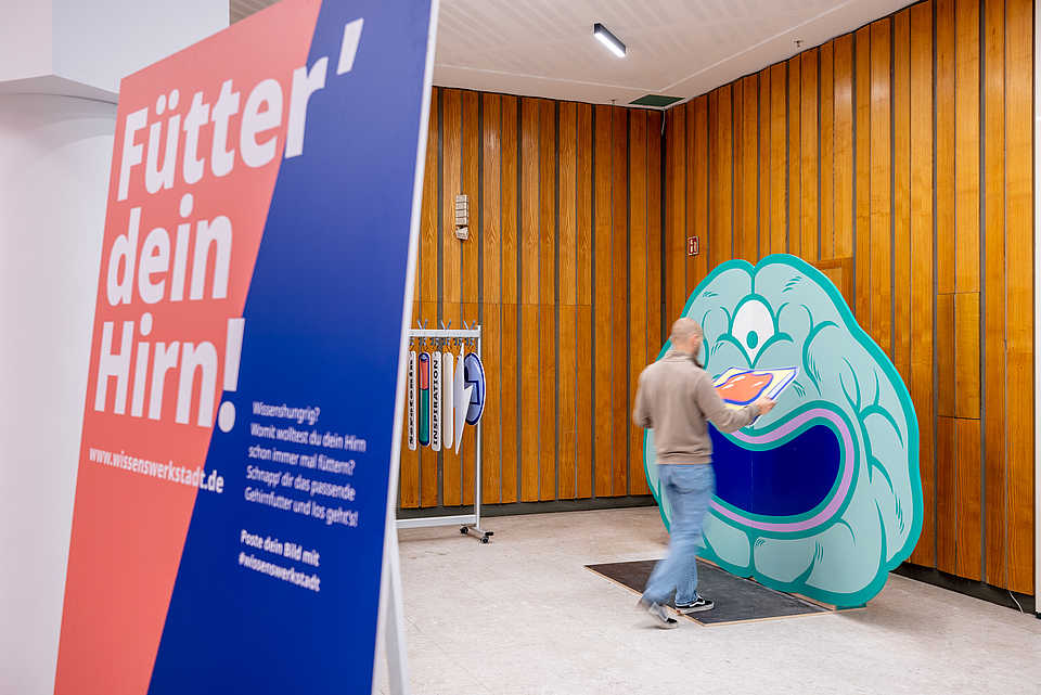 Interaktiver Ausstellungsbereich der WissensWerkStadt Bielefeld mit einer auffälligen Installation eines Gehirns und einem Schild mit der Aufschrift 'Fütter dein Hirn!'.