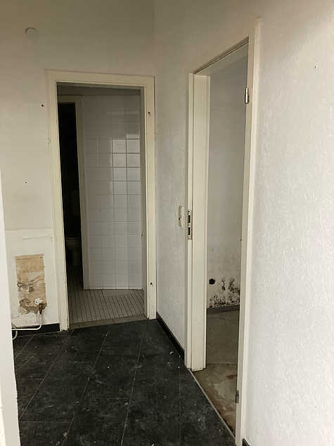 Ehemaliger Friseursalon mit Waschbecken und weißen Fliesen, leerstehend vor der Modernisierung.
