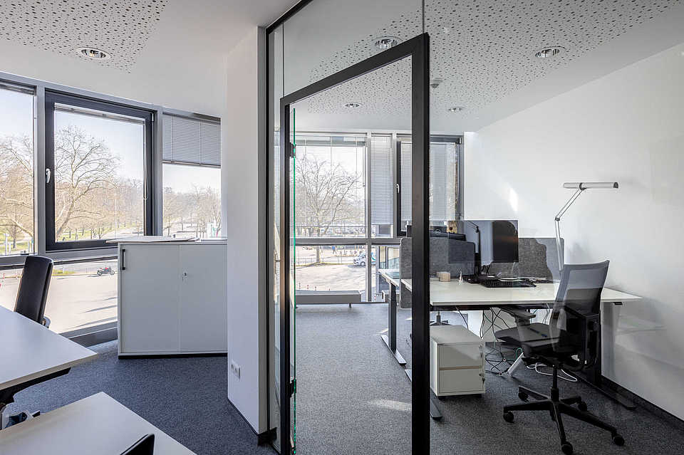 Modern eingerichtetes Büro mit großen Fenstern und viel Tageslicht.